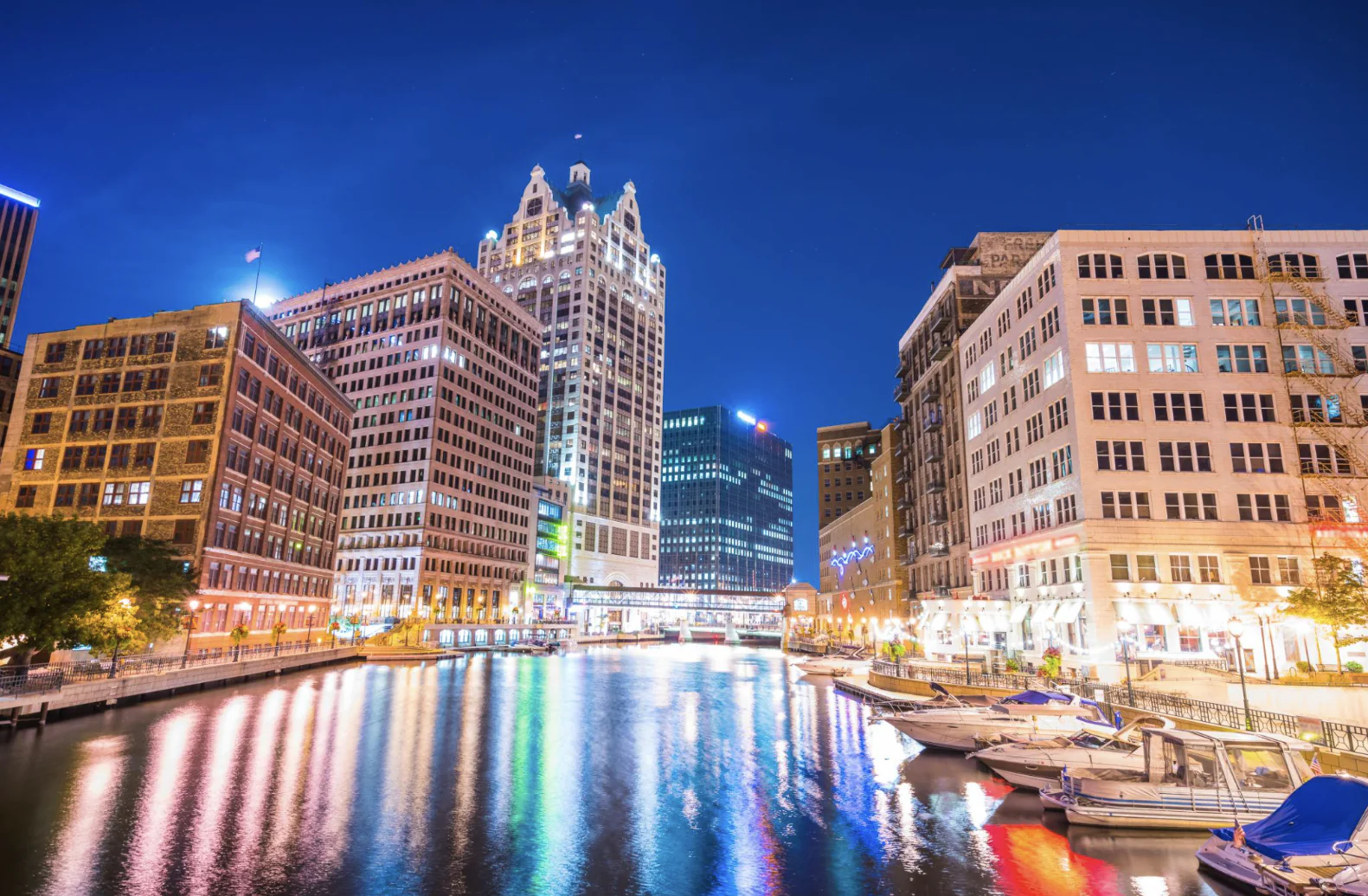 The Milwaukee city skyline and bridge illuminated at night over the river